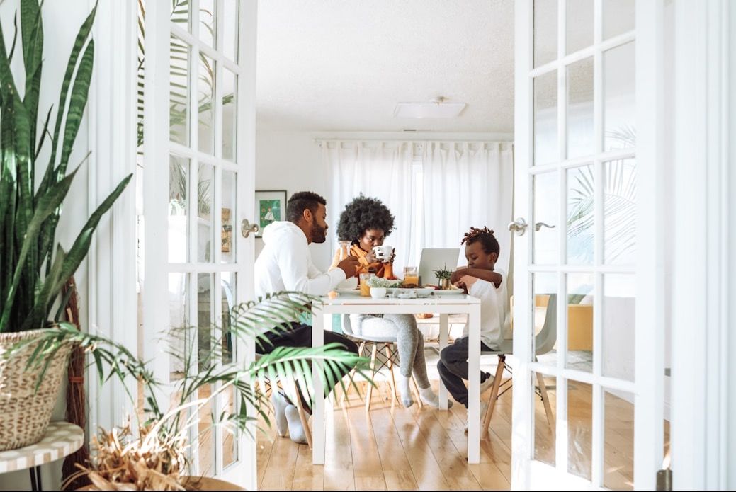 A family gathered around a table at home, seen through an open doorway
