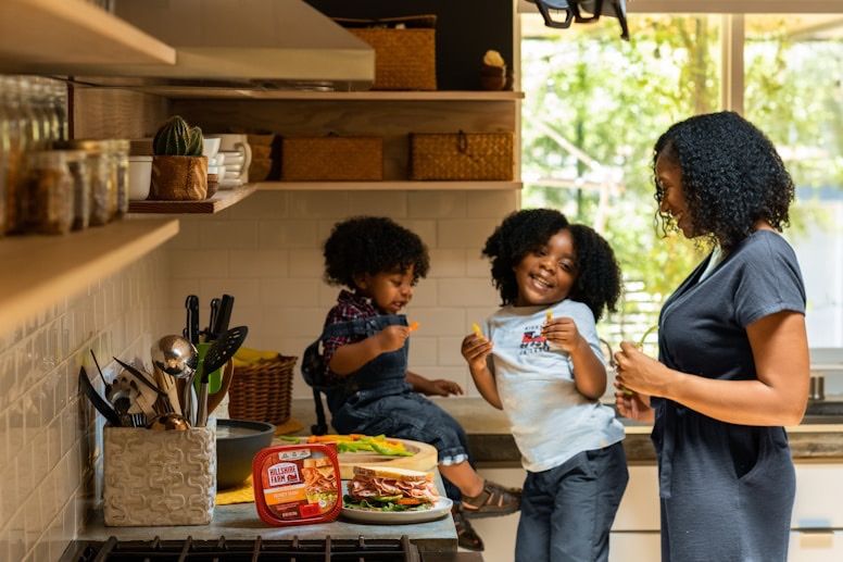 Parents and their two children laughing together in a sunny kitchen