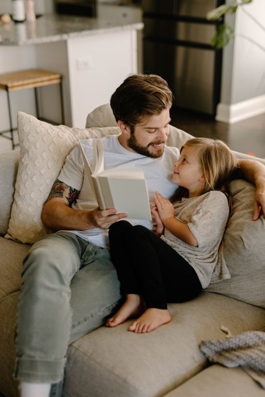 A father and daughter reading together on a sofa